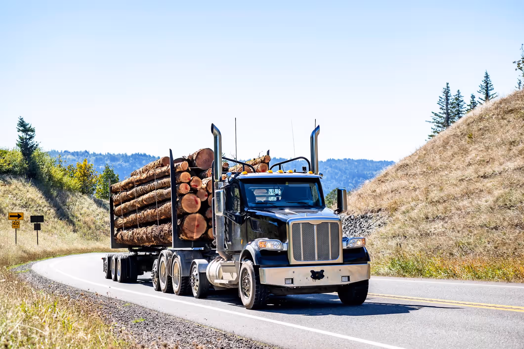 logging truck loaded with timber driving on a mountain road